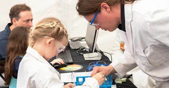 Ein Wissenschaftler betreut ein Mädchen bei einem chemischen Experiment