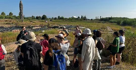 Studierende an Ausgrabungsstätte in praller Sonne.