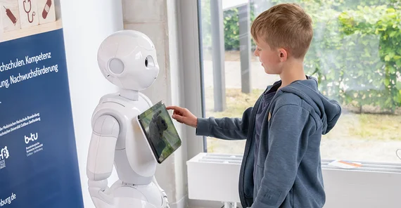 Kind interagiert mit Roboter.