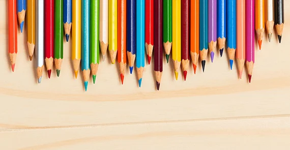 Buntstifte liegen nebeneinander auf einem Tisch.