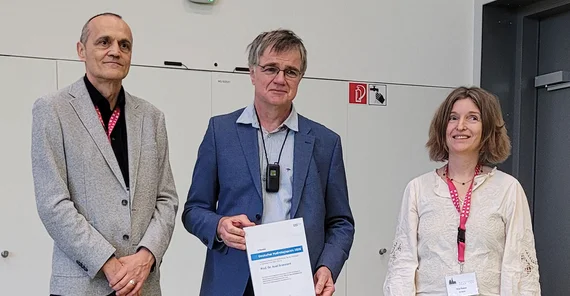 Drei Personen posieren für ein Pressefoto.