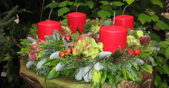 Adventsgesteck mit vier roten Kerzen.