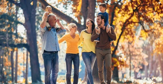 Eine glückliche Familie von drei Generationen steht in einem Park.
