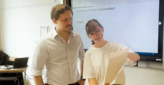 Ein Mann und eine Frau schauen auf ein Blatt.