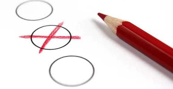 Wahlzettel mit einem gezeichneten roten Kreuz und dem daneben liegenden Stift