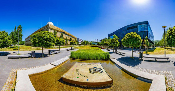 Aufnahme von zwei Gebäuden, in der Mitte ein Wasserspiel