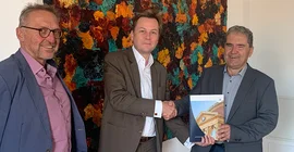Professor Joachim Ludwig (l.) und Professor Gisbert Fanselow (r.) übergeben die von 260 Beschäftigten unterzeichnete Selbstverpflichtung zum Verzicht auf dienstliche Kurzstreckenfüge an den Präsidenten der Universität, Prof. Oliver Günther, Ph.D. (Foto: Universität Potsdam/Horn-Conrad).