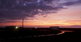 Bild mit Sonnenuntergang und Bohrturm im Hintergrund