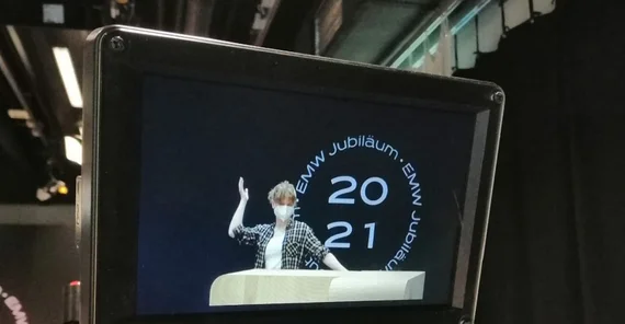 Das Foto zeigt das Bild einer laufenden Fernsehkamera; darauf eine Studentin mit Mund-Nasen-Schutz. Das Foto ist von Lukas Krähn.