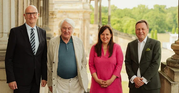 Vier Personen stehen auf der Freitreppe des Süd-Communs