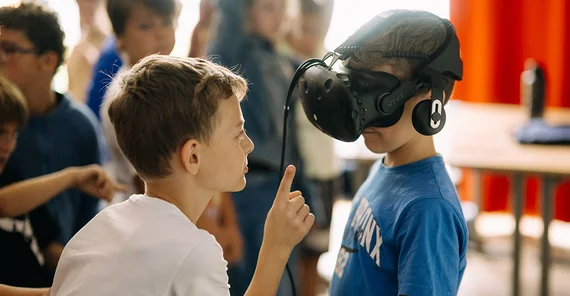 Zwei Kinder im Fokus. Eins trägt eine VR-Brille.