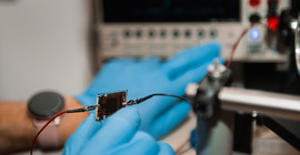 Zwei Hände, die ein Bauteil für eine Solarzelle halten.