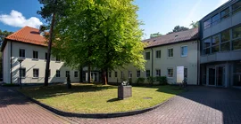 The German Institute of Human Nutrition (DIfE) in Rehbrücke. Exterior view of the building. In the foreground, you can see a green area with a large deciduous tree.