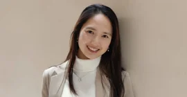 Das ist ein Porträtfoto. Es zeigt eine Frau vor einem hellbraunen Hintergrund.