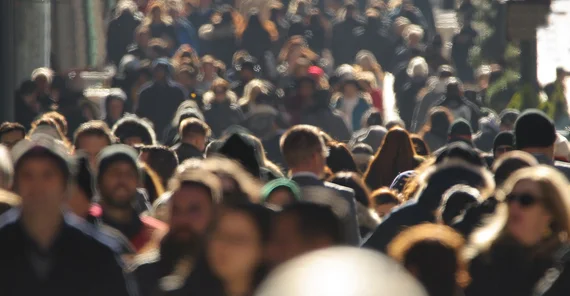 Blick in eine Menschenmenge auf einem Gehweg. Kein Gesicht ist klar auszumachen.