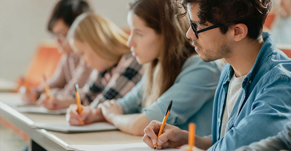 An der Uni Potsdam studieren rund 2.900 Menschen mit gesundheitlichen Einschränkungen. Studierende sitzen in einer Bankreihe im Seminarraum. Das Foto ist von AdobeStock/Gorodenkoff.