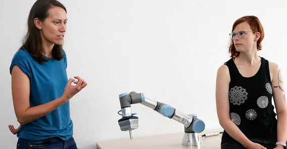Dr. Jana Götze (l.) und Dr. Maike Paetzel-Prüsmann mit industriellem Roboterarm.