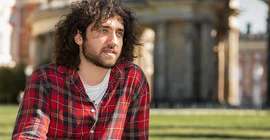 Student Hikmet Güler sitzt am Campus Neues Palais