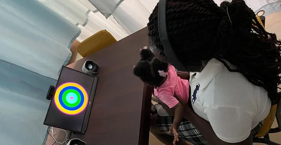 Sprachstudie in Gahana. Mutter und Baby sitzen vor einem Bildschirm