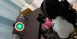 Sprachstudie in Gahana. Mutter und Baby sitzen vor einem Bildschirm