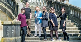 Gruppenfoto von 5 Frauen und einem Mann auf den Treppen am Neuen Palais