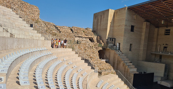 Ein Teil eines Amphittheaters ist modern bestuhlt. Der Rest zeigt archäologische Funde. Die moderne Bühne mit "Nicken" zur ursprünglichen historischen Herkunft ist ebenso zu erkennen.