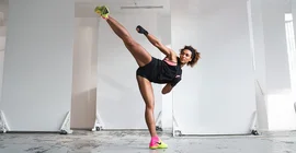Marie Mouroum during sporting activity – her right leg is raised above her head in a high kick.