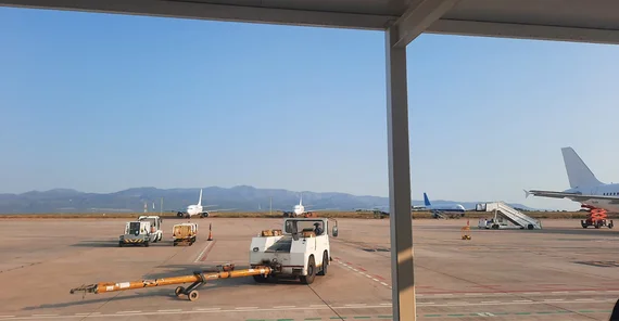 Flughafen von Castellón mit Flugzeugen und Flughafenfahrzeugen im Vorder- und Mittelgrund. Im Hintergrund Berge und darüber wolkenloser Himmel.
