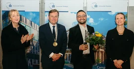 Vier Menschen stehen bei einer Preisverleihung zusammen