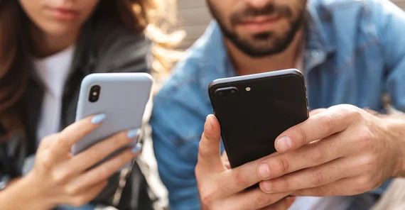 Eine Frau und ein Mann halten ein Smartphone in den Händen.