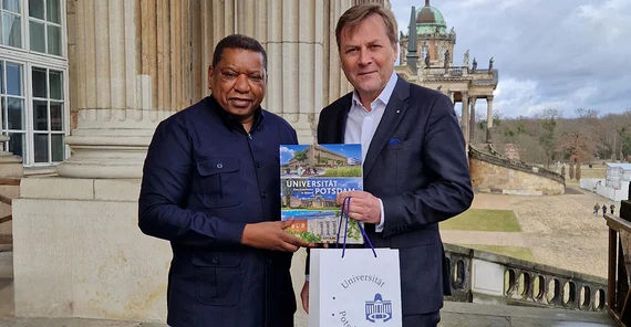 Two people posing for photo. They are shaking hands.