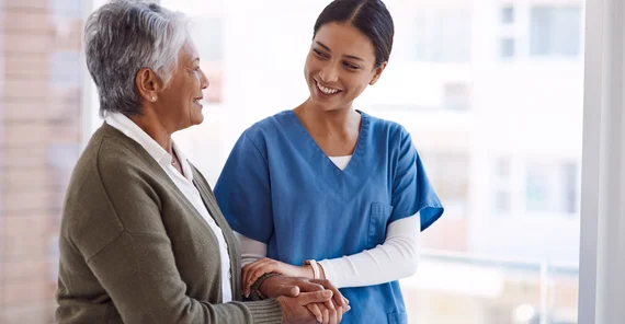 Eine Pflegerin stützt eine ältere Frau.