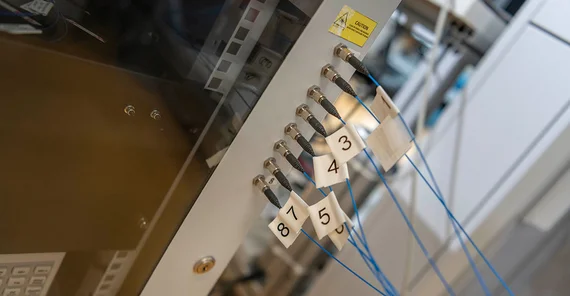 Zimmermann connects the fiber optic cables of the measuring probe for photon density wave spectroscopy, which is in the reactor, to the spectrometer.