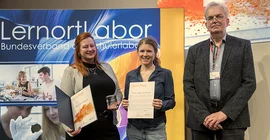 Zwei Frauen und ein Mann posieren für ein Foto bei einer Preisverleihung