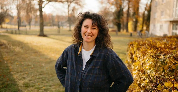 Dorotheé Steinbock im legeren Pulli offen lachend vor winterlich-herbstlicher Kulisse an einem Campus der Uni Potsdam.