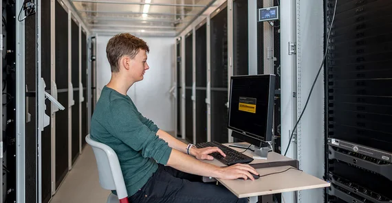 Person sitzt im Serverraum. Das Foto ist von Thomas Roese.