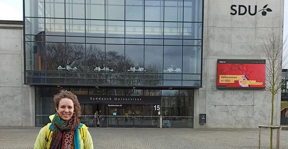 Eine Frau steht vonr einem Uni-Gebäude in Odense