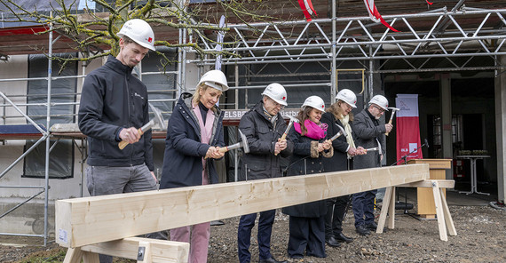 6 Menschen hämmern Nägel in einen großen Balken